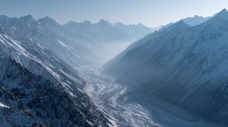 Breathtaking aerial view of a snow-covered mountain valley shrouded in mist, showcasing the natural beauty of wilderness and serene landscapes in winter.の素材