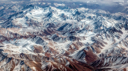 This breathtaking aerial photography captures the stunning beauty of snow-capped mountain peaks amidst dramatic textures and colors, showcasing nature's serene grandeur.の素材
