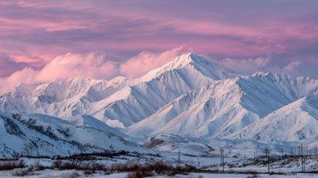 Stunning snow-capped mountains rise majestically against a vibrant pink sky at dawn, creating a breathtaking winter landscape in remote wilderness, perfect for nature lovers.の素材