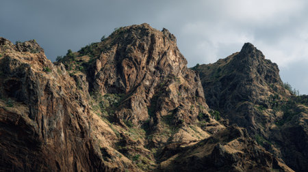 Experience the breathtaking beauty of rocky peaks beneath a dramatic sky, where clouds and sunlight create striking contrasts in a serene wilderness landscape.の素材