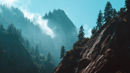 Explore a breathtaking view of majestic mountains adorned with misty peaks and lush trees. The scene captures the serene beauty of a natural landscape under a radiant blue sky.の素材