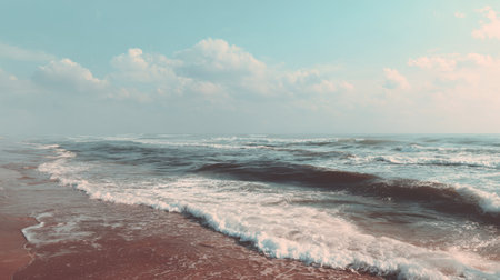 Enjoy a breathtaking view of gentle ocean waves caressing a sandy beach under a soft, cloudy sky, creating a serene atmosphere perfect for relaxation and contemplation.の素材