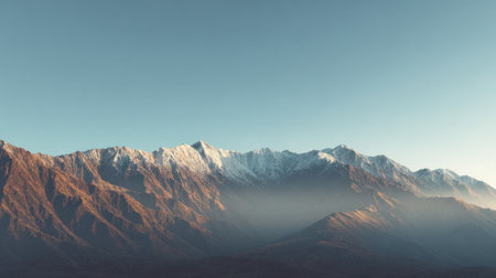 This stunning image captures a snow-capped mountain range bathed in soft morning light. The mist adds a tranquil touch to the expansive landscape, inviting exploration.の素材