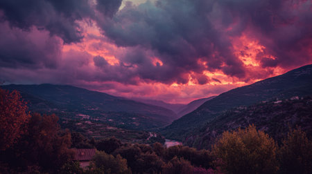 A stunning view of a dramatic sunset illuminating a serene valley surrounded by majestic mountains and colorful clouds, creating a captivating natural scene.の素材