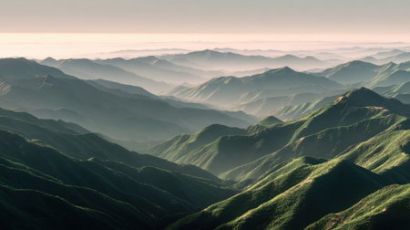 Experience a stunning mountain landscape featuring lush green hills layered beneath soft sunlight and a tranquil mist, perfect for nature lovers and adventurers.の素材