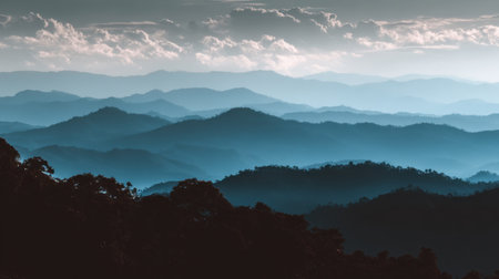 Discover a breathtaking mountain landscape with layers of blue hues and soft clouds, showcasing tranquility and natural beauty during dusk. Perfect for nature lovers.の素材