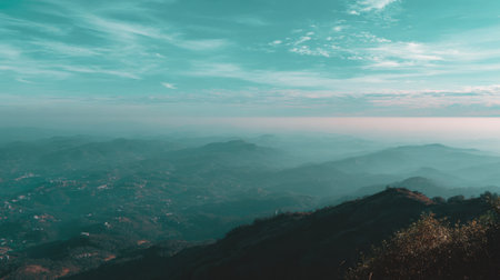 Experience the breathtaking beauty of a misty valley surrounded by rolling hills under a clear sky at dawn, embodying nature's serene tranquility and vibrant colors.の素材