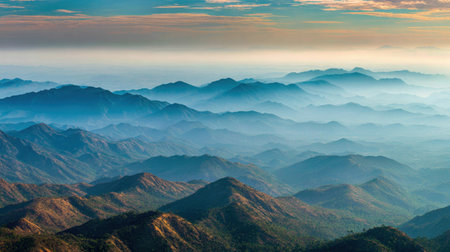 This breathtaking mountain landscape showcases layered peaks under a soft fog, creating a tranquil atmosphere. The captivating colors of dawn highlight natureの素材