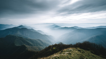 Explore a breathtaking mountain landscape enveloped in fog beneath an overcast sky, perfect for nature lovers and adventure seekers seeking tranquility.の素材