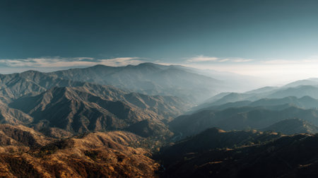 Experience the breathtaking beauty of a majestic mountain range under a clear blue sky, showcasing the captivating layers of hills and smoky horizons.の素材