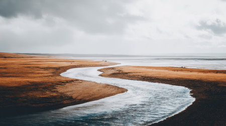 A tranquil river gracefully winds through a golden landscape under an expansive and dramatic cloudy sky, evoking a sense of peace and natural beauty.の素材