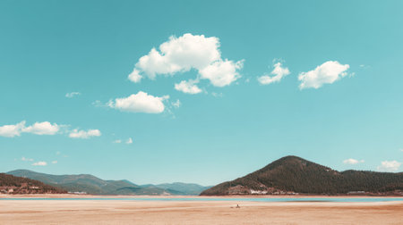 A serene landscape featuring a deserted lake shore under a bright blue sky with fluffy clouds, encapsulating nature's tranquility and scenic beauty of outdoor environments.の素材