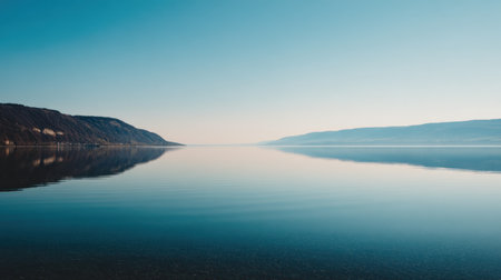 This tranquil image captures a serene lake with stunning reflections of a clear blue sky and distant mountains, embodying the essence of natural beauty and peacefulness.の素材