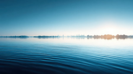 A tranquil view of a serene water surface showcasing gentle ripples under a calm blue sky at dawn, reflecting the peaceful atmosphere of a natural landscape.の素材