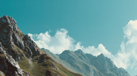This stunning mountain landscape features rocky cliffs and vibrant greenery under a brilliant blue sky adorned with fluffy clouds, perfect for nature lovers and adventurers.の素材