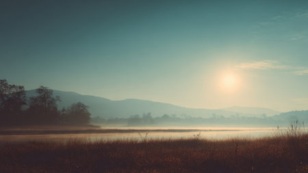 A breathtaking dawn scene featuring mist rising over calm waters, with mountains in the background and soft sunlight illuminating the tranquil landscape.の素材