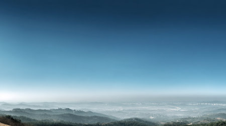 Breathtaking view of rolling hills shrouded in soft mist under a clear blue sky at dawn, creating a serene and tranquil atmosphere in nature's embrace.の素材
