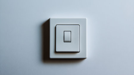 A sleek white light switch is positioned on a smooth surface, exemplifying modern design principles. This image captures the essence of minimalism in home technology.の素材