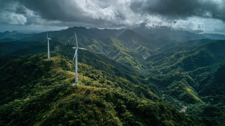 Aerial view of a stunning mountainous landscape featuring wind turbines amidst lush greenery and dramatic skies, highlighting the importance of renewable energy in ecology.の素材