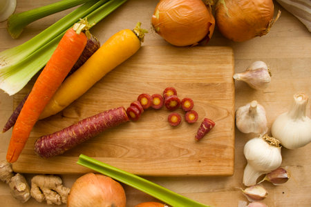 Sliced carrot surrounded by an assortment of fresh vegetables.の写真素材