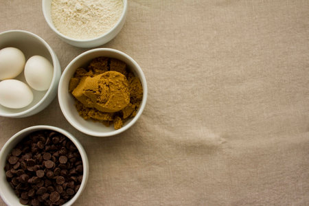 White bowls with ingredients-- chocolate chips, eggs, brown sugar and flour.