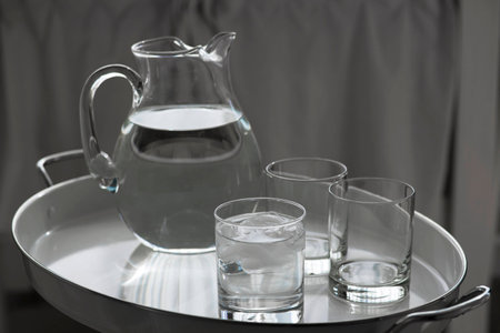 A pitcher of water with glasses on a white tray.の写真素材