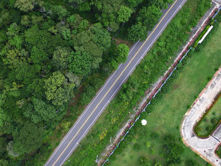 Aerial drone view of country road between green forest