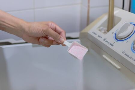 She is washing clothes and She put the detergent in the washing machine. She will wash clothes every Wednesday and Saturday. Don't leave clothes too long. May have germs.の写真素材