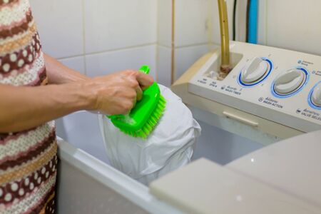 She Scrubbing brush to remove stains on shirt. To prepare to put the clothes into the washing machine. Don't leave clothes too long. May have germs.の写真素材