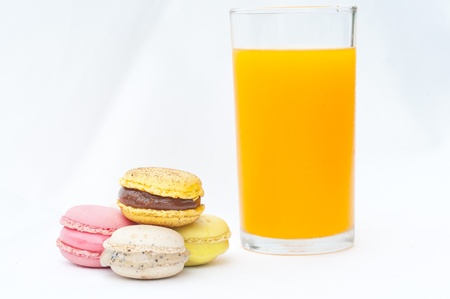 Colorful macaroons whith orabge juice glass on white background の写真素材