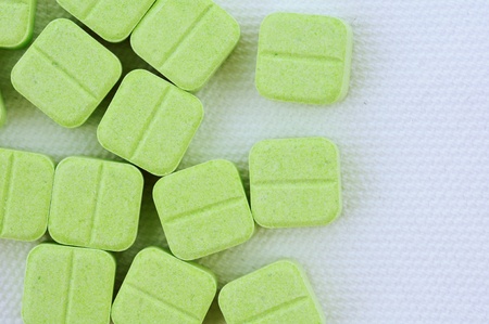 Green medicinal pills piled up a bunch of closeup isolate on white background. 