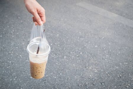 Woman handing a cup of cool coffee with blurred the road for background.の写真素材