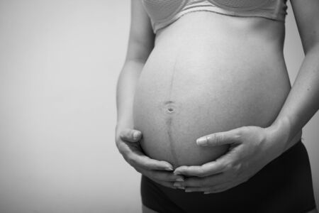 Woman are pregnant on gray background. The abdominal section of the womb. Pregnancy is about 7 months. Black and white image.の写真素材