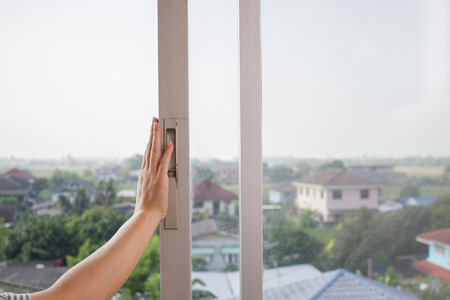 Woman's hand opens the old sliding glass window. Selective focus.の写真素材