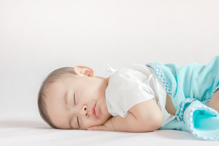 The baby sleeps upside down on the bed. Selective focus.の写真素材
