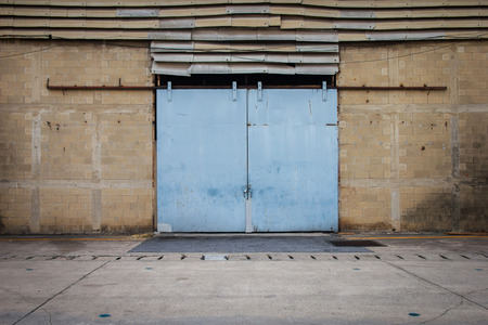 Large steel doors of old warehouses are closed. Old warehouses with large steel doors.の写真素材