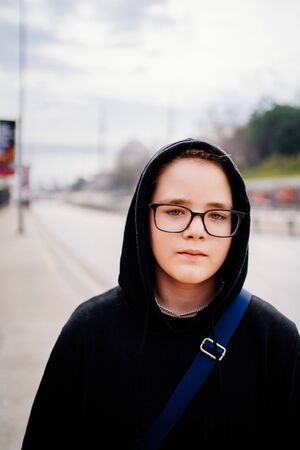 teenager with glasses and a black hood on the background of the city of Istanbul close-upの写真素材