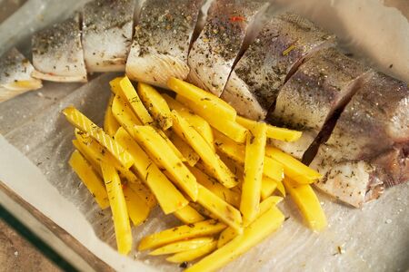cooking. fish and potatoes raw in a glass pan for bakingの写真素材