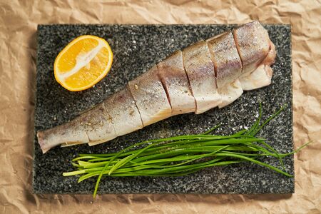 raw fish lemon and green onions on a black Board. cooking. cooking at home, recipes, dishes and menusの写真素材