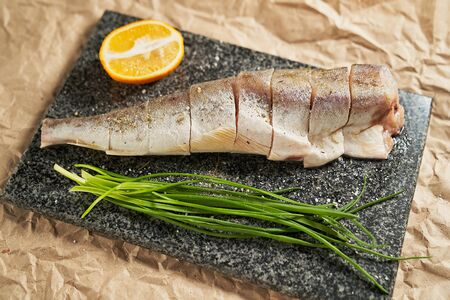 raw fish lemon and green onions on a black Board. cooking. cooking at home, recipes, dishes and menusの写真素材