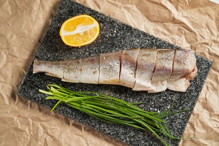 raw fish lemon and green onions on a black Board. cooking. cooking at home, recipes, dishes and menusの写真素材