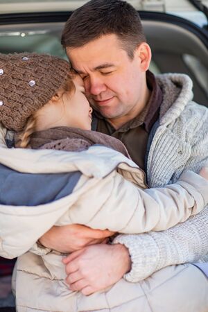A daughters in a hat is with father in winter clothes. Love in the family.の写真素材