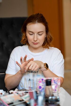 the girl is going to do her makeup sitting at the table with cosmeticsの写真素材