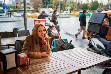 Beautiful girl in a street cafe a phone in her handsの写真素材