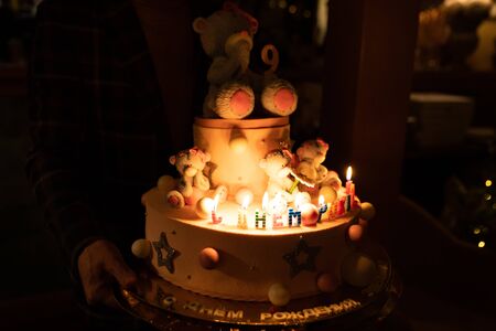 cake with a bear and candles for a birthday party for a child in the dark.の写真素材