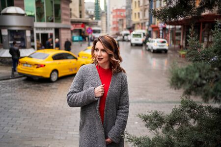 A girl stands near the road against the background of a taxiの写真素材