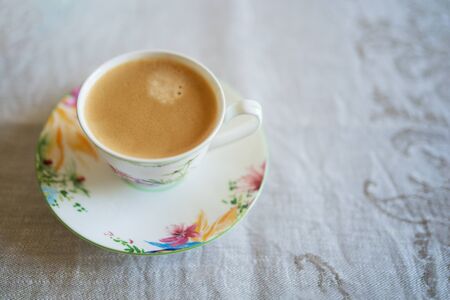 coffee with milk in a beautiful Cup top view on a table with a tablecloth in flowers free spaceの写真素材