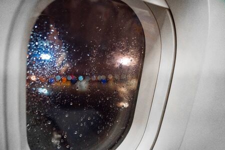 colored drops on the plane window at night reflection of lanternsの写真素材