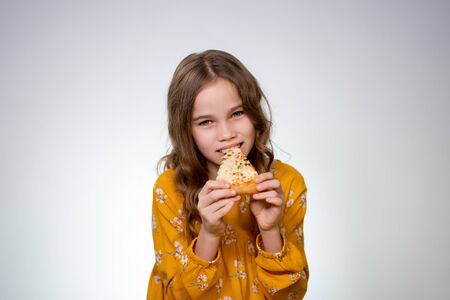 the Teenager girl with curly hair biting and eating pizza on a white background. Delicious food.