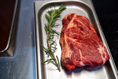 Raw meat with rosemary on a metal tray. The kitchen of the restaurant. The chef prepares the order.の写真素材